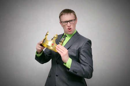 Selfish arrogant man holding in hands a golden crown. Winner concept. Customer with high self-esteem.の写真素材
