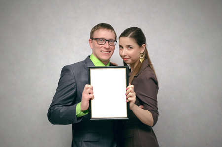 Happy satisfied young pair couple is holding in hands a blank diploma certificate with copy space. Best family of the year concept.の写真素材