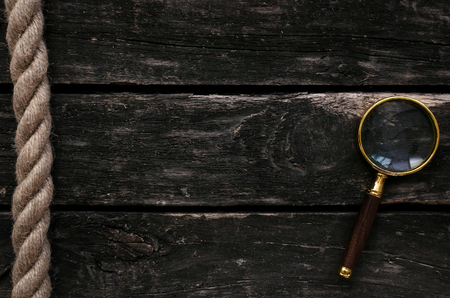 Magnifying glass and hawser rope on wooden table background.の写真素材
