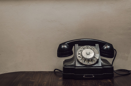 Retro rotary telephone on the table on wall background with copy space. Visiting card design.の写真素材