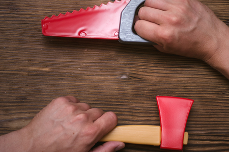 Toy saw and axe in hands. Construction background with copy space.の写真素材