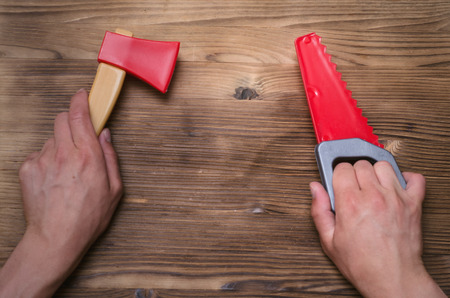 Toy saw and axe in hands. Construction background with copy space.の写真素材