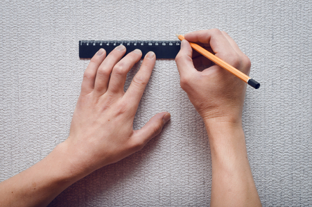 The builder marks on the wall with a ruler and pencil the dimensions for the hole.の写真素材