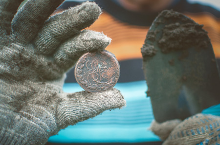 Aged 5 kopeks coin of Russian empire in the hand of coin finder. Treasure hunting concept. In search of a lost treasure.の写真素材
