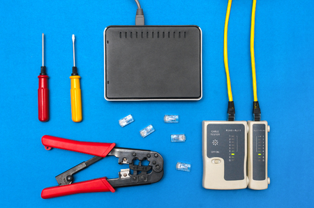 Cripmer tool, network cable tester and a switch router isolated on the blue background. Network maitenance concept.の写真素材