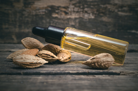 Almond nut oil in the bottle on the wooden table background.の写真素材