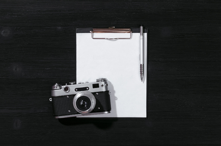 Shot list mockup. Photo session contract template. Vintage film photo camera and blank paper page on black wooden table background. Flat lay design.の写真素材