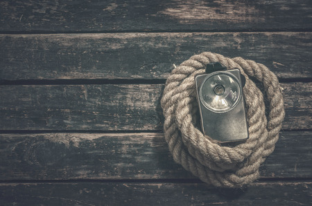 Rope and retro flashlight on the wooden table surface background with copy space. Adventurer or...