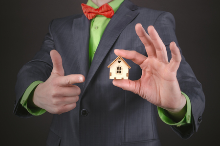 Small toy house in a real estate agent hands on a black background. Home insurance. Buy a house special offer concept.の写真素材