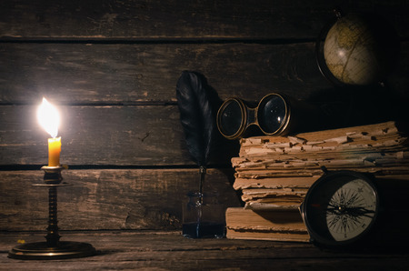 Travel or adventure concept background. Compass, binoculars, globe map, stack of books, quill pen on the adventurer table.の写真素材