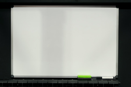 Blank white blackboard with copy space hanging on the black wall background.の写真素材