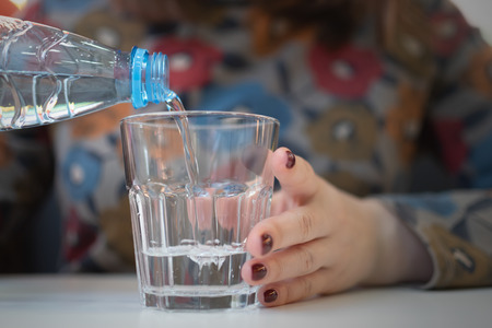 Woman pouring a cold water in a transparent glass in her hand.の写真素材