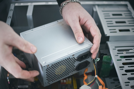 Computer engineer is installing a power supply into a computer.の写真素材