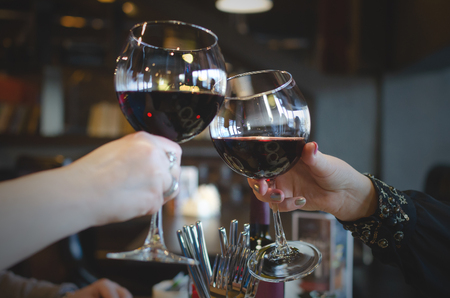 People are clinking wine glasses with red wine and talking a celebration toasts.の写真素材