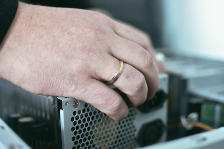 Computer engineer is installing a power supply into a computer.