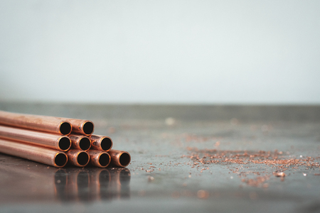 Stack of brass pipes on a fitter workbench background with copy space.の写真素材
