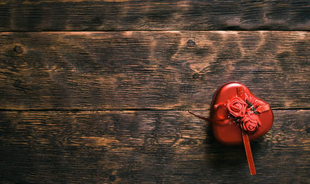 Red empty heart shape gift box on aged brown wooden table background with copy space.の写真素材