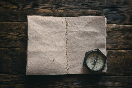 Blank traveler notebook and nautical compass on a wooden table background mockup. Adventurer notes.