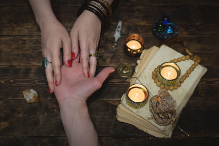 Palmistry concept. Fortune teller reading future on the hand on a magic table background. Future reading concept.の写真素材