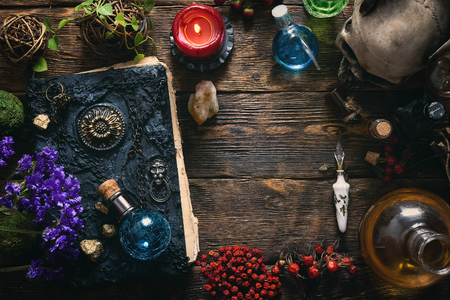 Spell book, magic potions and other various witchcraft accessories on the wizard table background with copy space.の写真素材