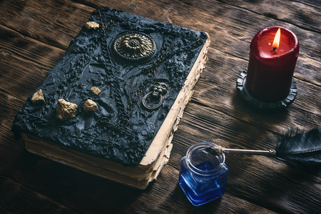 Ancient magic book, ink well and a quill pen on a wooden table background. Spell book.の写真素材