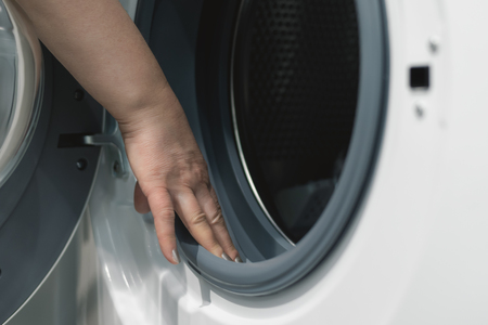 A young woman is choosing a new washing machine for home. Buying a new wash appliance.の写真素材