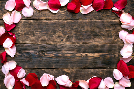 A pile of fallen rose flowers petals on a wooden floor background with copy space.の写真素材