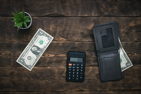 Calculator, wallet and a few dollars on a table. Tight of money. Lack of money. Financial problems....