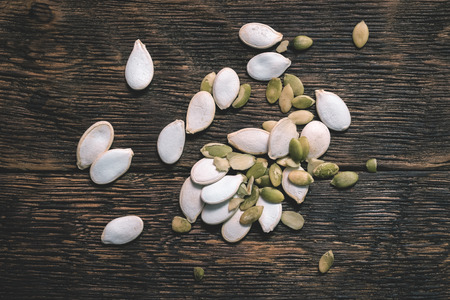 Scattered pumpkin seeds on the wooden table background.の写真素材