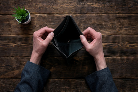 Empty wallet in hands on an office table background. No money concept. Debts. Bankruptcy.