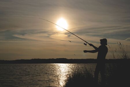 Fisherman silhouette with a rod on the pond.の写真素材