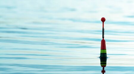 Fishing float in a blue water close up background.