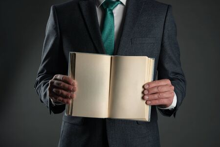 Open book with blank pages in a business man hands on a gray background.の写真素材