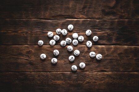 Scandinavian stone runes on a brown wooden table background. Futune reading concept.の写真素材