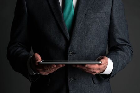 Digital tablet computer in a business man hands on gray background. Buy or sale online. Internet...