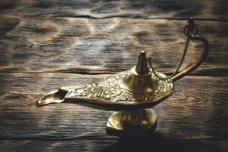 A golden Genie lamp on a wooden board background.の写真素材