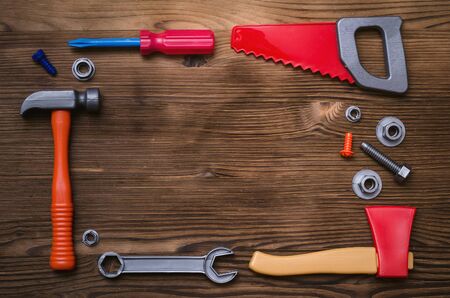 Construction background with copy space. Toy hammer, saw and axe on carpenter desk table.