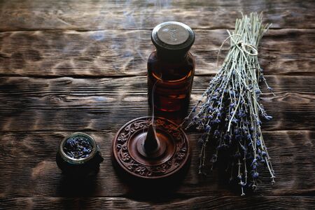 Dried lavender flower branches and lavender essential oil bottles on a wooden table background. Herbal medicine or aromatherapy concept.の写真素材