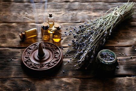 Dried lavender flower branches and lavender essential oil bottles on a wooden table background. Herbal medicine or aromatherapy concept.の写真素材