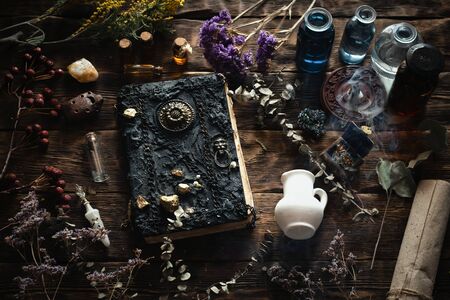 Magic recipe book and a magic potions on a table. Witchcraft background with copy space. Druid or witch doctor table.の写真素材