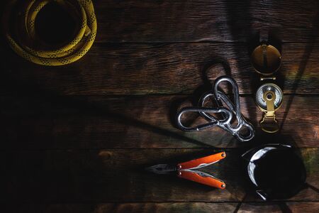 Travel or adventure equipment and accessories abstract flat lay background. Compass, safety rope, carabines, multi tool knife and a flashlight on the tourist table.の写真素材