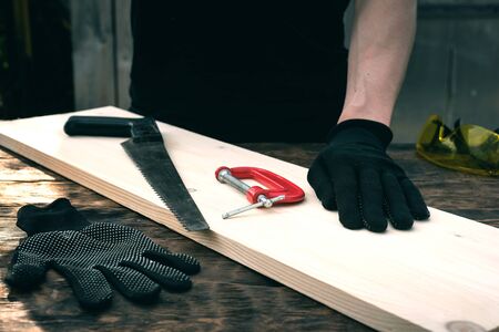 Worker is holding a wooden bar on a workbench. Woodwork. Carpentry.