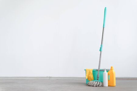 Bucket with a mop and bottle of detergent on a floor on a white wall background with copy space. Wet cleaning concept background.の写真素材