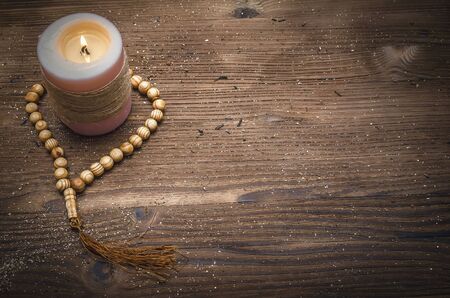Beads and burning candle on wooden table background with copy space. Meditation.