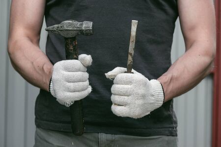 Carpenter is holding in hands a chisel and hammer.の写真素材