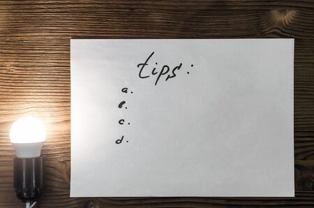 Tips note paper page on wooden desk table surface background with copy space in the light of burning...