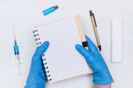 Doctor is writing a record to blank page notepad on the doctor table background. Medical journal or...
