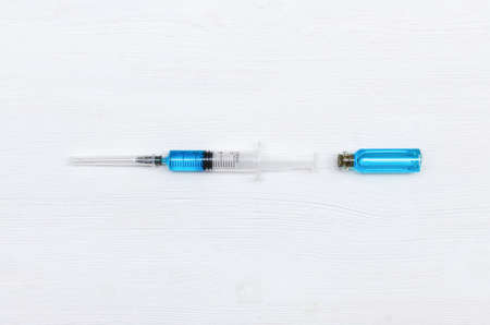 Syringe and ampoule with blue liquid medicine on the doctor table.