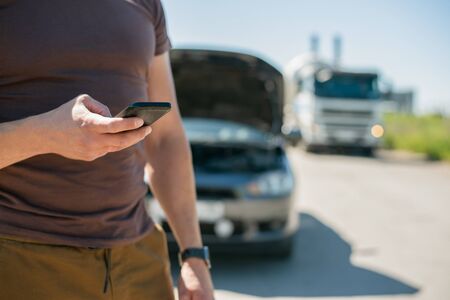Driver is calling with his mobile phone to a car tow truck service.