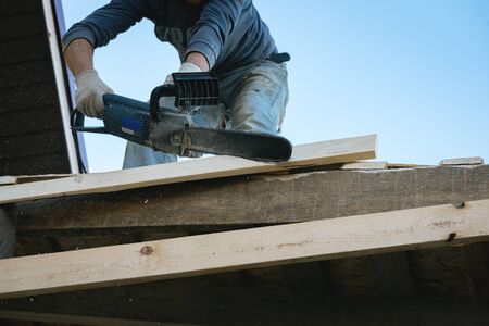 Worker is cutting a wood by a chainsaw.